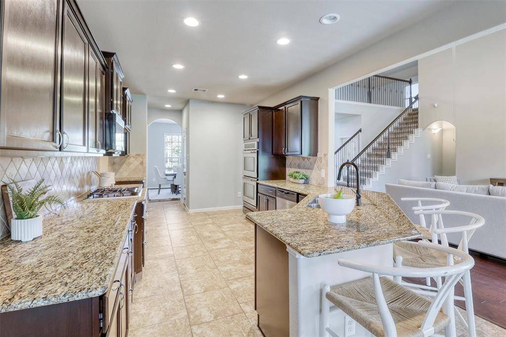 This fully equipped kitchen is a chef’s dream with granite countertops, dark espresso cabinetry, stainless steel appliances, under-cabinet lighting, and a coordinating backsplash for a classic, elevated feel.