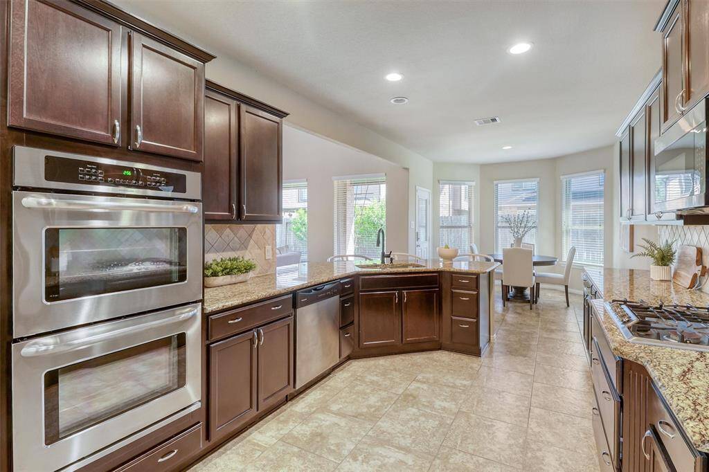 The kitchen layout maximizes counter space and storage, offering double ovens, a built-in microwave, and an abundance of cabinets to keep everything neatly organized.