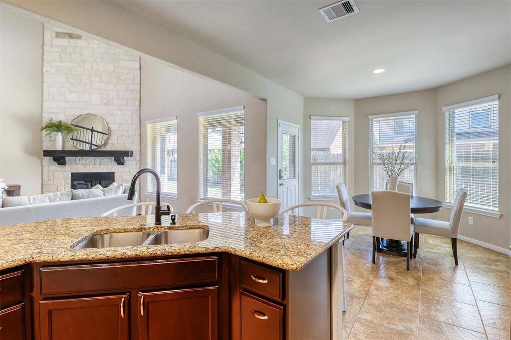 The kitchen effortlessly flows into the sunlit breakfast room, where a wall of windows overlooks the backyard—bringing natural light and warmth to every morning meal.