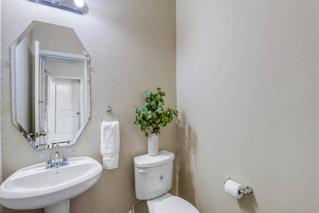 The conveniently located half bath on the main floor features a pedestal sink, designer mirror, and modern lighting—perfect for guests and everyday use.