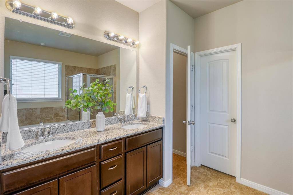 Step into the ensuite bath, where a dual-sink granite vanity offers ample space for daily routines and spa-like moments alike.