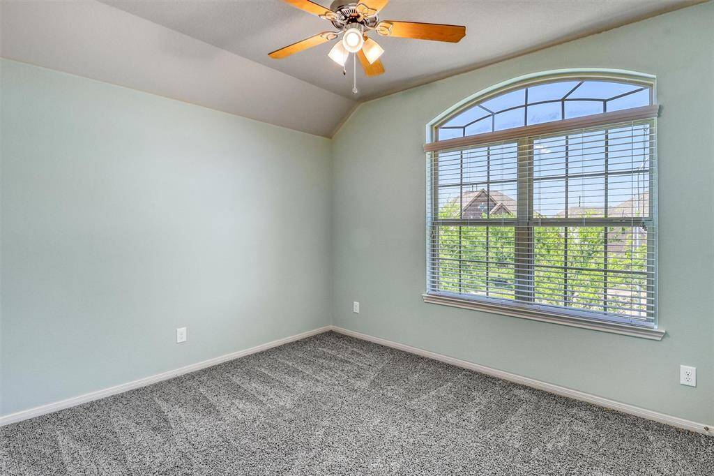 Vaulted ceilings and a stunning arched window give the third bedroom a spacious, sunlit feel with a ceiling fan for added comfort.
