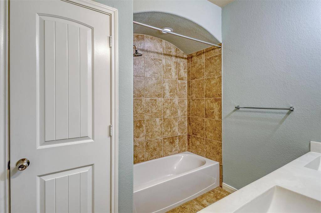 A dual-sink vanity and fully tiled shower/tub enclosure provide style and functionality for busy mornings.