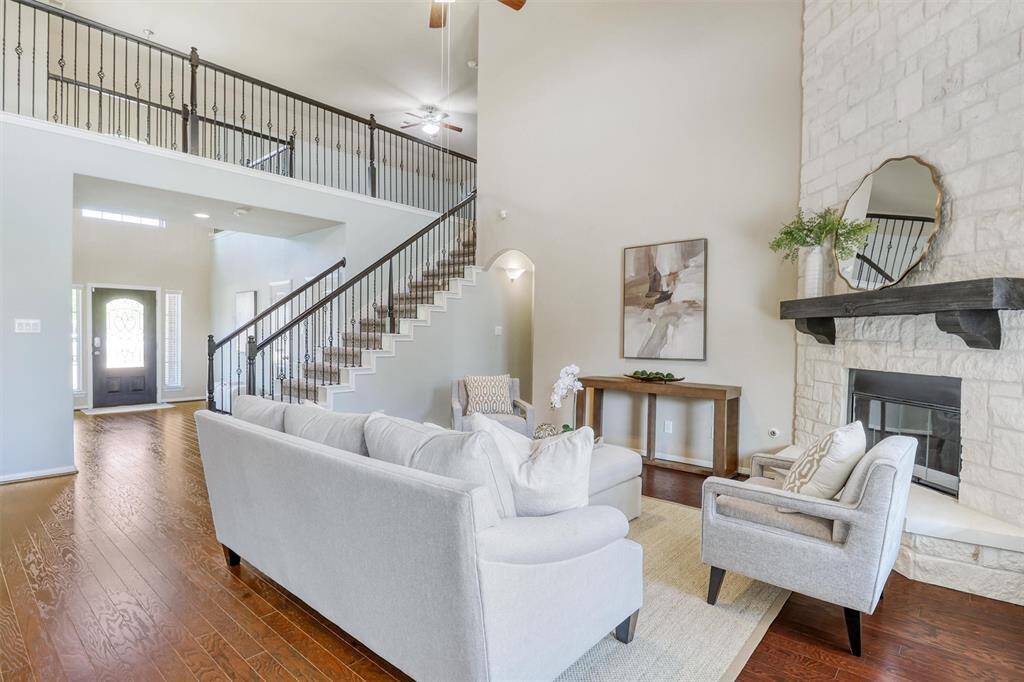 This view highlights the dramatic scale and openness of the home, with sightlines to the front entry and a stunning two-story stone fireplace anchoring the heart of the living space.
