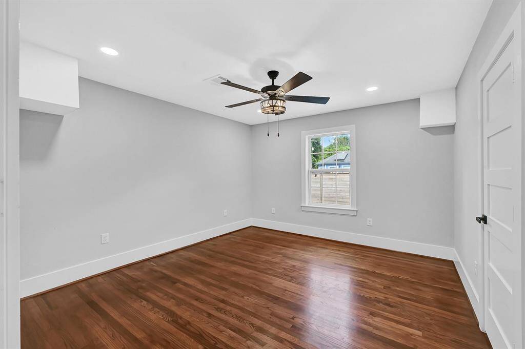 This inviting bedroom features a large window that fills the space with natural light, a modern ceiling fan for year-round comfort, and stylish custom paint that adds a personal touch of charm.