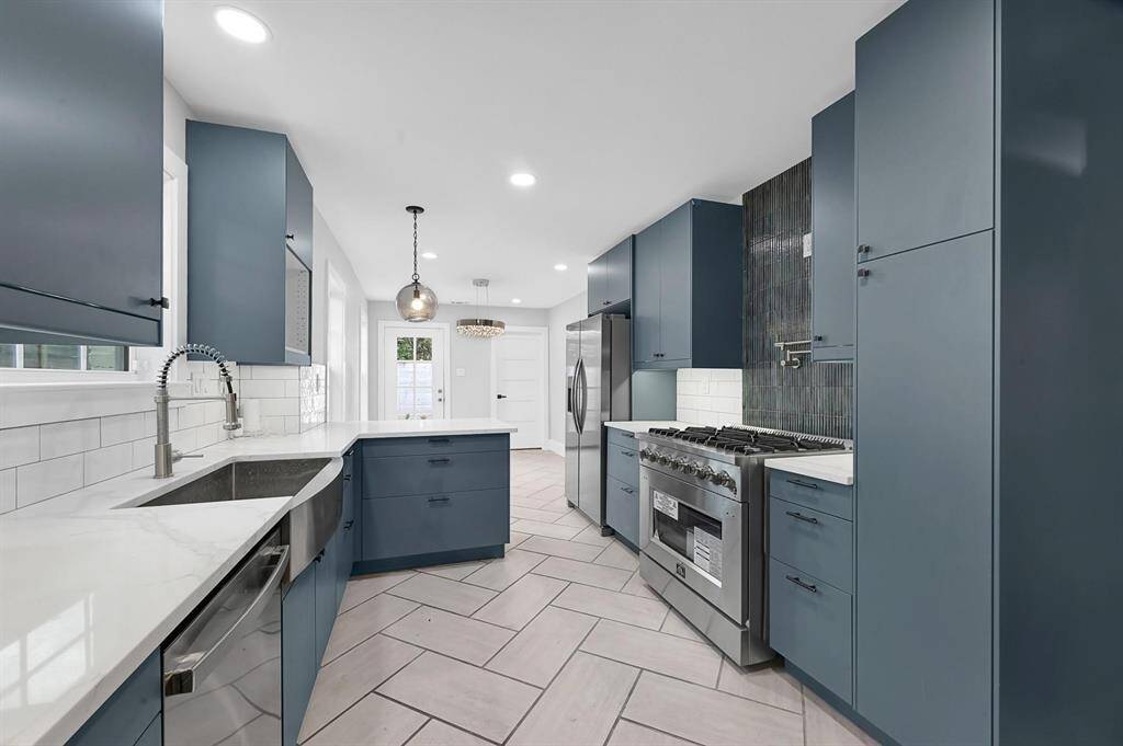 This modern kitchen boasts custom-painted cabinetry, a sleek stainless steel gas stove with a convenient kettle faucet, and a stainless steel dishwasher—blending style and functionality for the perfect culinary space.