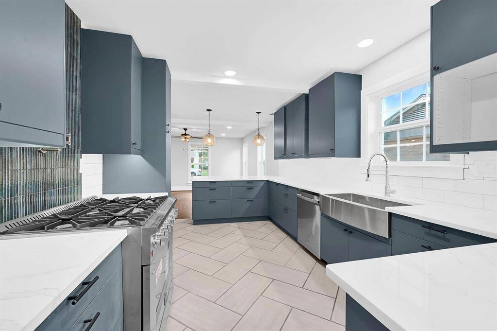 Enjoy another stunning view of the kitchen featuring a stainless steel farmhouse sink perfectly positioned under a window, accented by a classic white subway tile backsplash and durable tile flooring—combining charm and practicality in every detail.