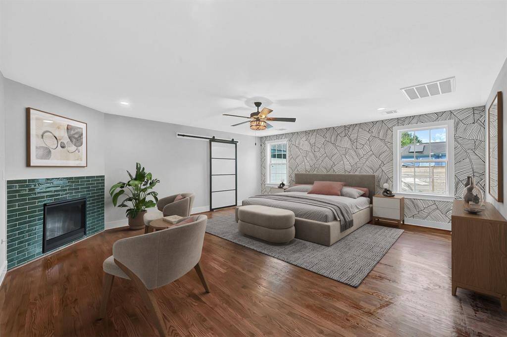 Retreat to the spacious primary bedroom featuring a stunning custom accent wall, abundant natural light from large windows, and your own private gas log fireplace adorned with stylish green tile—creating a cozy and sophisticated sanctuary to unwind in. *Virtually Staged*