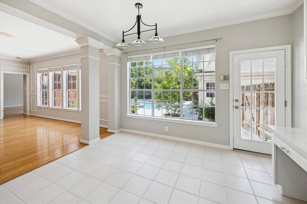 No detail has been overlooked in this stunning family room, featuring rich hardwood floors with a convenient floor plug, fresh neutral paint, and exquisite millwork including custom built-ins, chair rail, picture frame, and crown molding. A romantic gas fireplace serves as the focal point, while a wall of windows offers tranquil views of the sparkling backyard pool, filling the space with natural light and warmth.