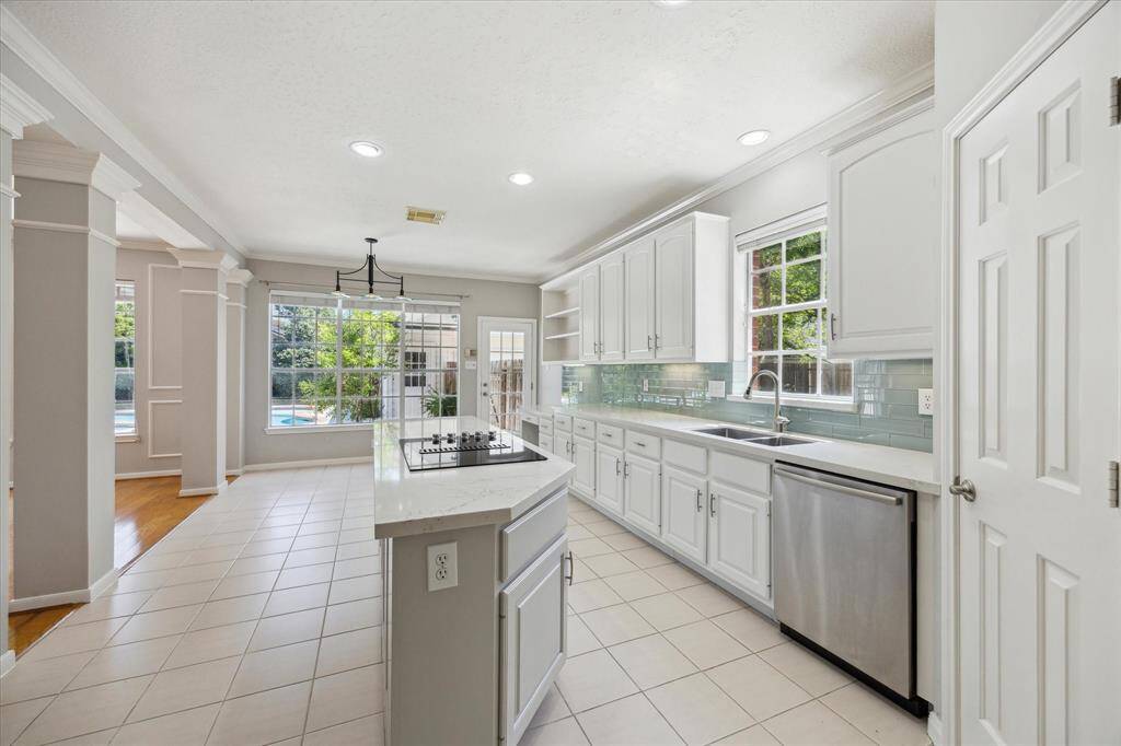 Show off your culinary skills in this beautifully updated kitchen featuring sleek Quartz countertops, designer tile backsplash, crisp white cabinetry with pots and pans drawers and updated pulls, under-cabinet lighting, updated appliances, and a spacious pantry.