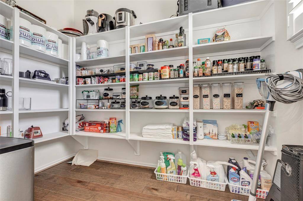 Huge pantry with ample shelving, perfect for storing various items such as kitchen appliances, food, and cleaning supplies. The space features white shelves against a neutral backdrop, creating a clean and inviting look. A rare feature in this community.