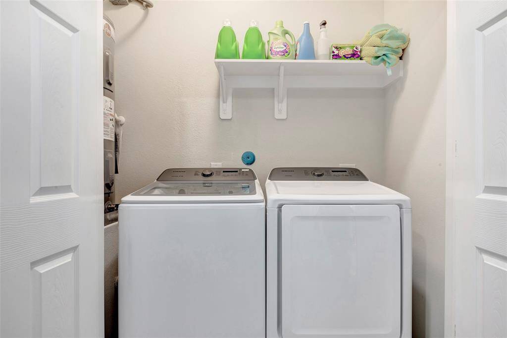 This is a compact laundry nook featuring a modern washer and dryer with a storage shelf above, neatly organized with laundry supplies.