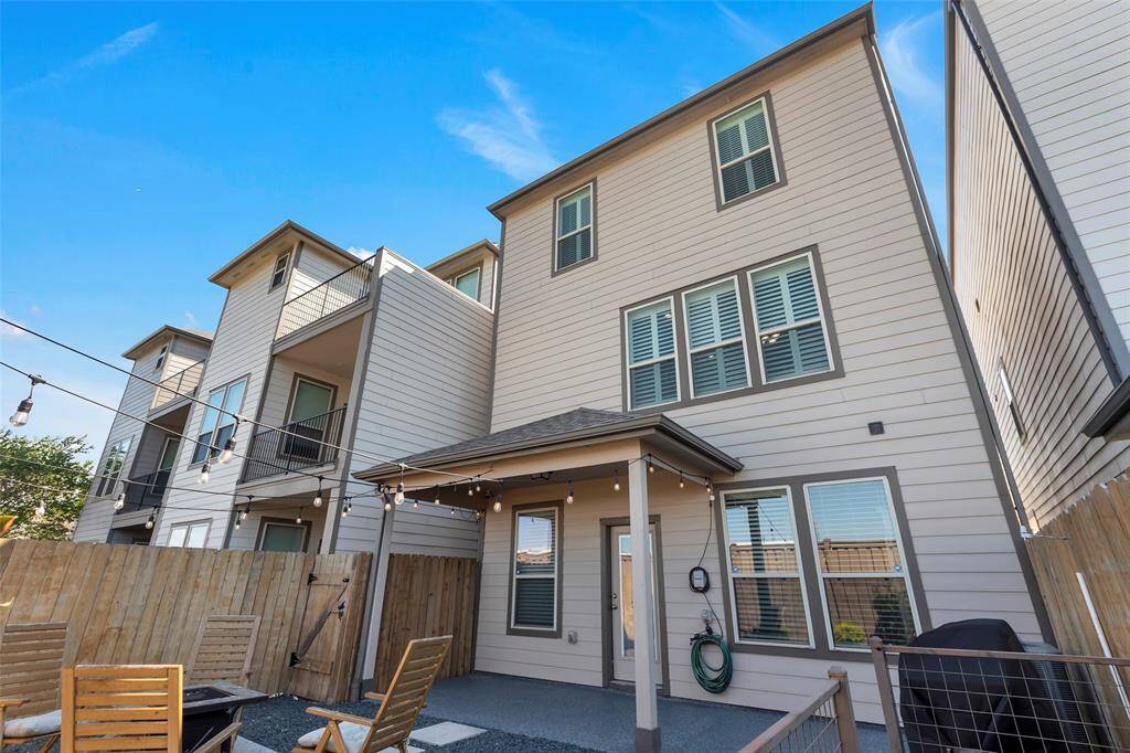 This is a three-story, modern townhouse with a neutral color palette, featuring a small fenced patio and balcony spaces, ideal for outdoor living. The home appears to have ample windows for natural light.