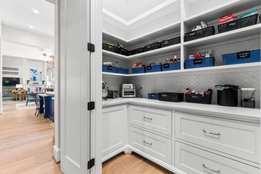 The pantry features elegant wooden cabinetry and open shelving, offering a spacious feel along with plenty of storage for all your kitchen essentials.
