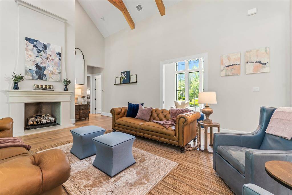 This spacious living room features high ceilings with exposed wooden beams, and a cozy fireplace. Perfect for relaxing or entertaining.