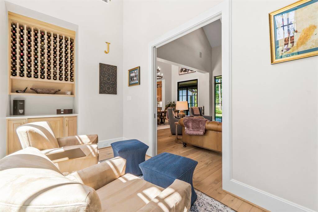 This inviting space features a cozy seating area with a built-in wine rack. The room opens into the bright living area with large windows, providing a view of the greenery outside. It combines elegance with functionality, perfect for relaxation and entertaining.