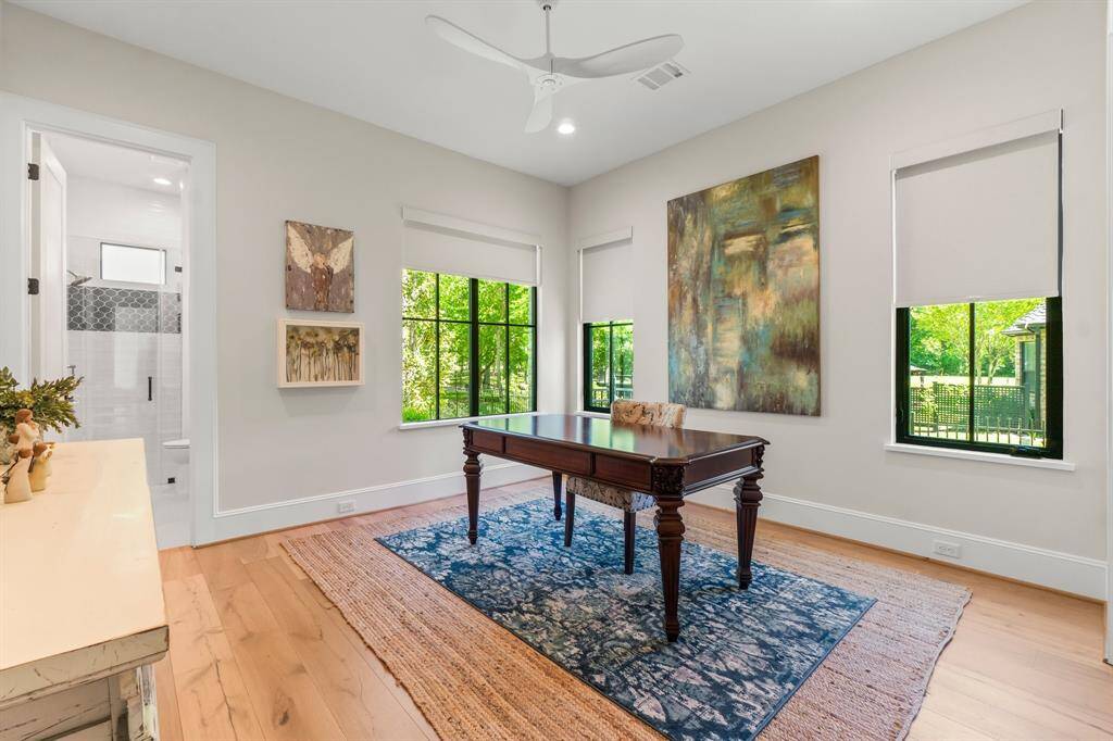 Bright home office/ bedroom with large windows offering lush green views.