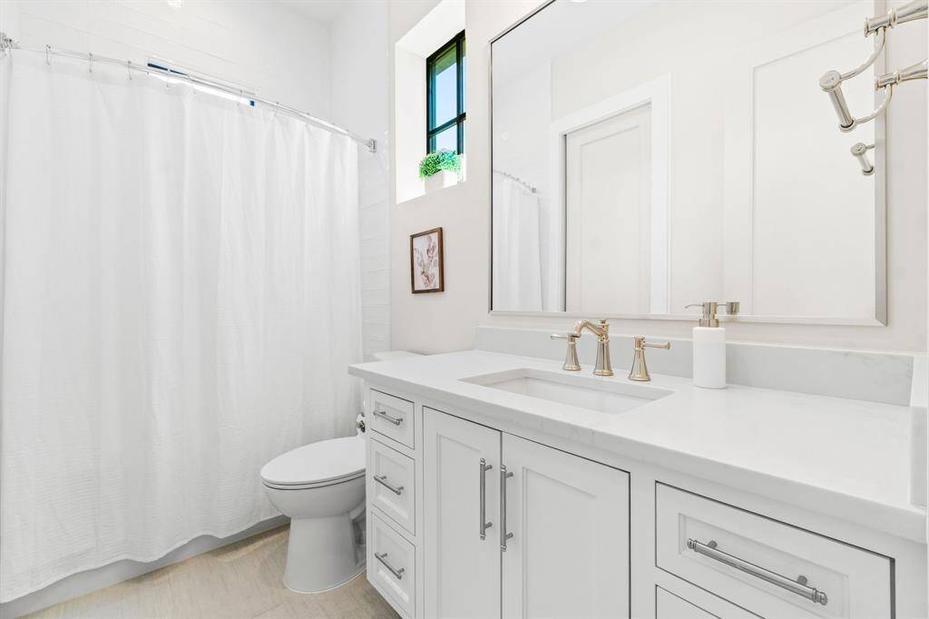 This bathroom features a modern design with a white vanity, sleek countertop, and stylish fixtures.