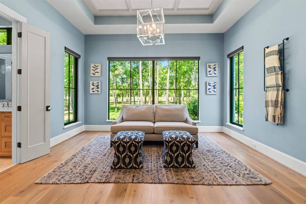 This inviting seating area features large windows that provide a beautiful view of the greenery, enhancing the natural light.