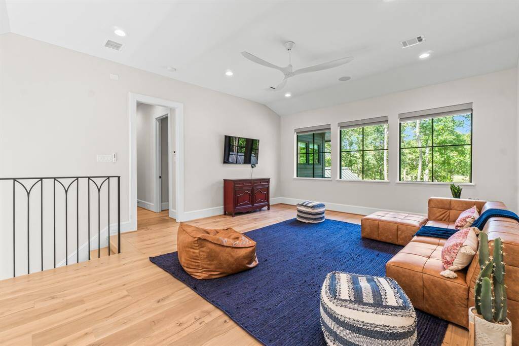 This bright, open living area features large windows with green views, a modern ceiling fan, and recessed lighting.
