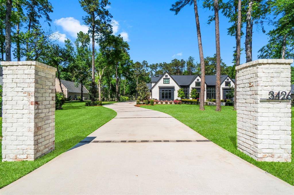 This photo showcases a modern, elegant home with a dark metal roof and large windows, set amidst lush greenery and landscaped gardens, offering a serene and inviting atmosphere.