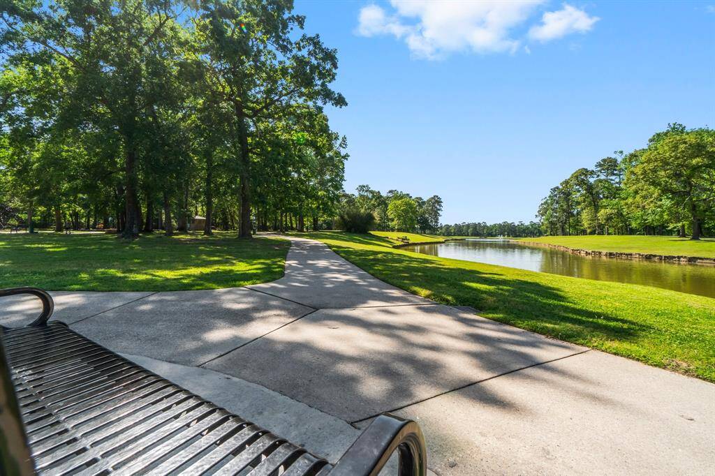 This photo captures the tranquil beauty of a serene lake encircled by lush green trees. A picturesque walking trail surrounds the lake, offering a perfect spot for leisurely walks and enjoying the natural scenery.