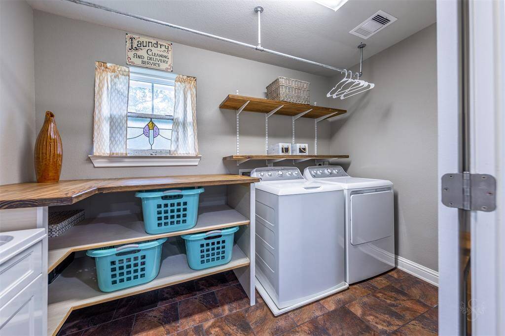 Second laundry room is located upstairs and has a sink and custom shelves designed to hold laundry baskets.