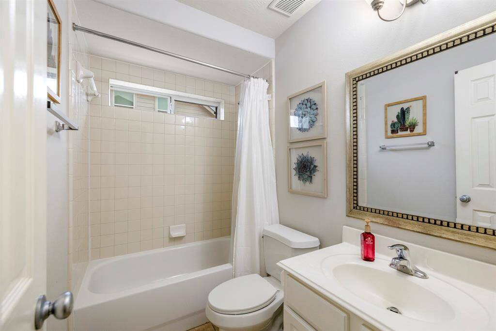 The downstairs full bathroom with white cabinets, a spacious tub and shower, and large vanity, is located just off the downstairs secondary bedroom, making it a perfect place for guests to unwind.