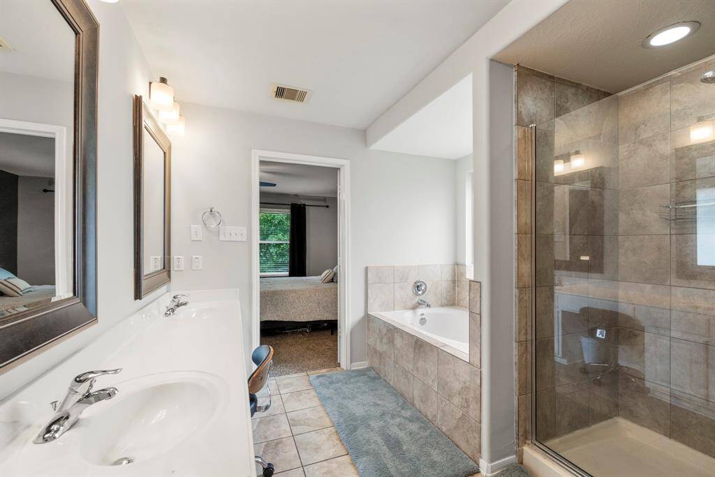You'll love getting ready in this light and bright primary bathroom! The primary bathroom includes a large vanity with dual sinks, white counters, framed mirrors, and white cabinets.