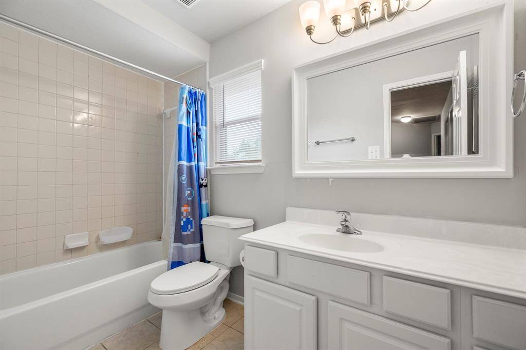 This full bathroom is located off the hall of the secondary bedrooms making it easy to share and get ready. It features a large vanity, white cabinets and countertops, and a large combination tub and shower.