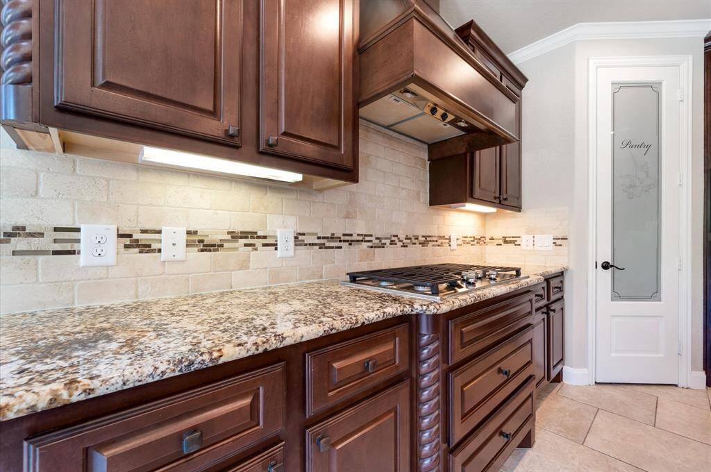 Unique exotic granite countertop with mosaic insert over tumbling marble backsplash with a gas stove.