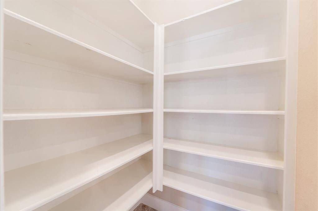 This spacious, well-lit pantry with multiple white shelves, ideal for organized storage.