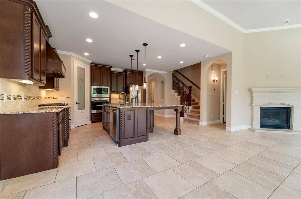 The open-concept design includes tile flooring, recessed lighting, and a fireplace, with a staircase leading to the upper level.