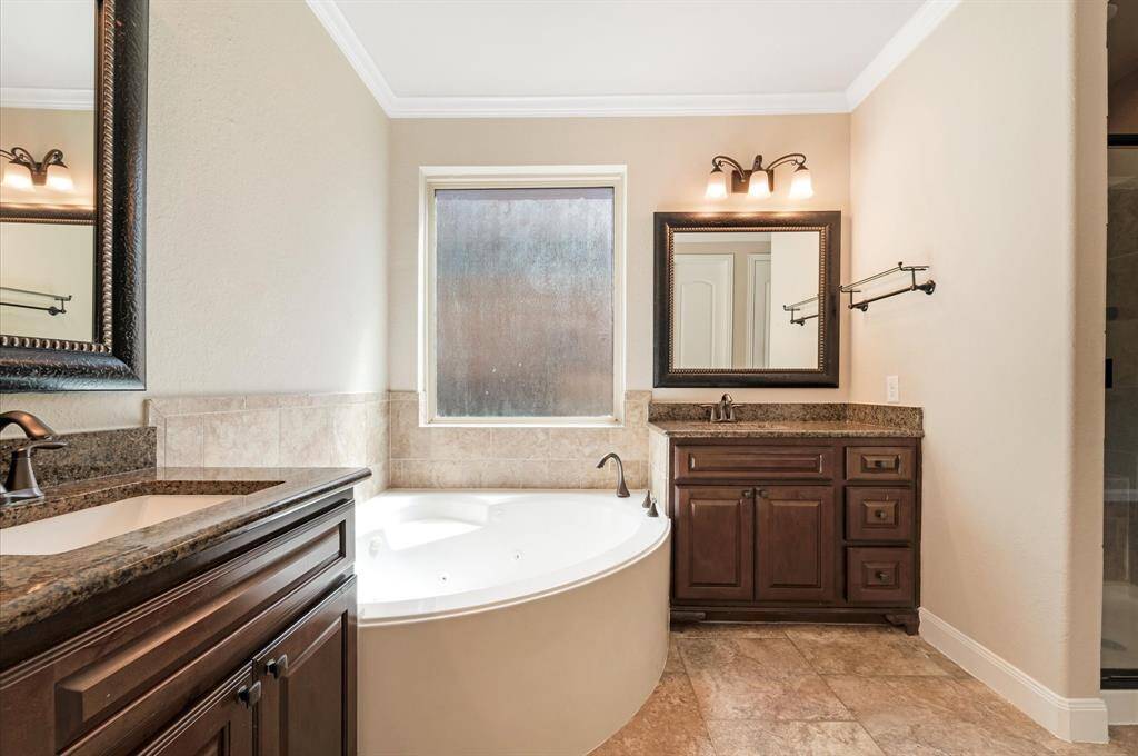 Additional view, corner soaking tub, dual vanities with granite countertops, and stylish dark wood cabinetry, with large mirrors, this Primary bathroom has an elegant lighting, with neutral tile floor.