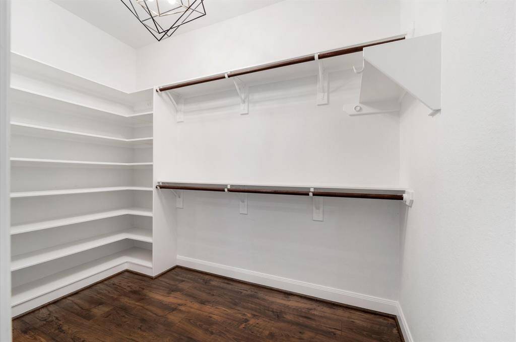 Spacious walk-in closet with ample shelving and hanging space, featuring LVP floors and a modern ceiling light. Btw this Primary Closet connects conveniently to the Laundry Room.