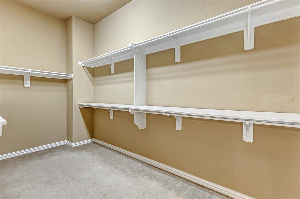 Spacious walk-in closet with built-in shelves and generous hanging space.