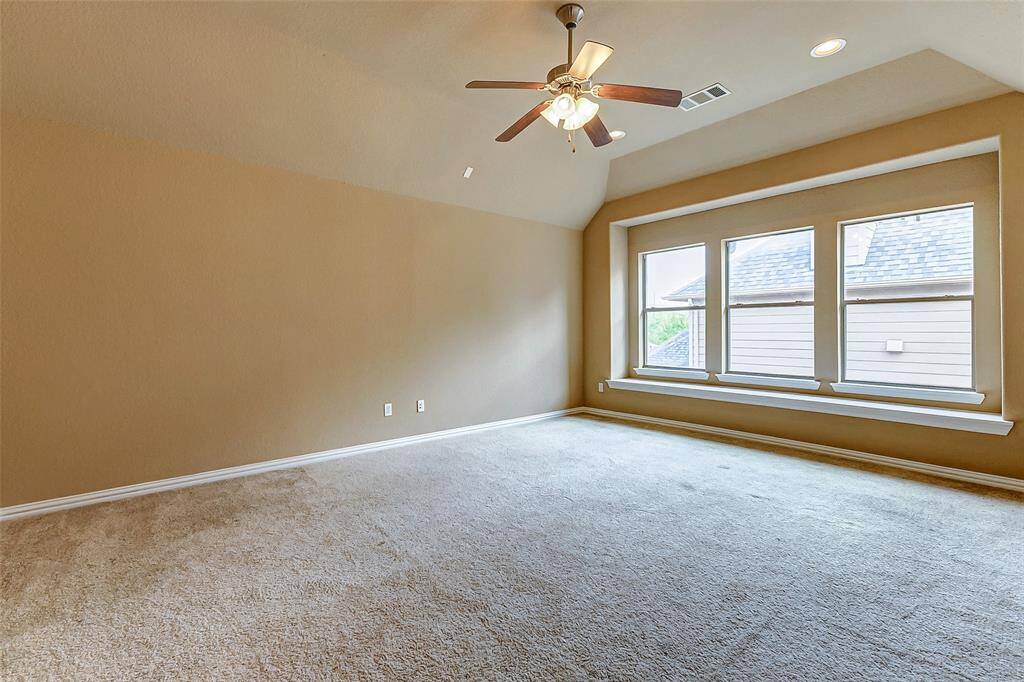 Spacious upstairs room with vaulted ceilings, large windows, and neutral finishes.