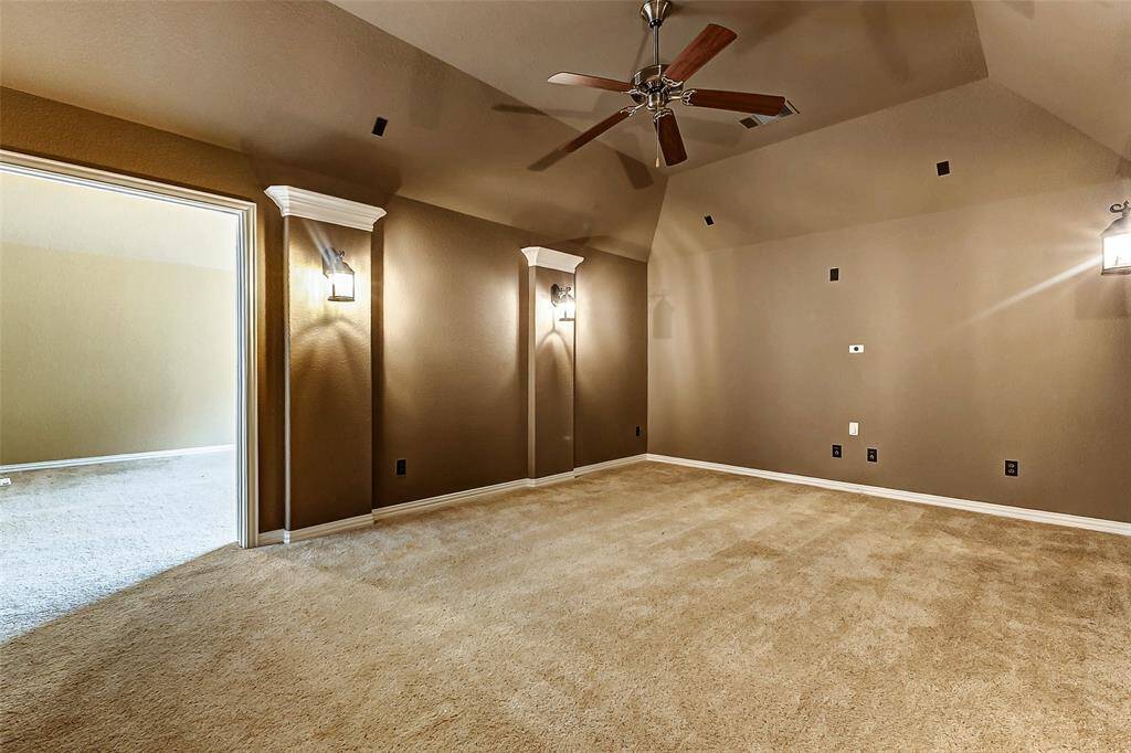 Cozy media room with dimmable wall sconces and vaulted ceiling