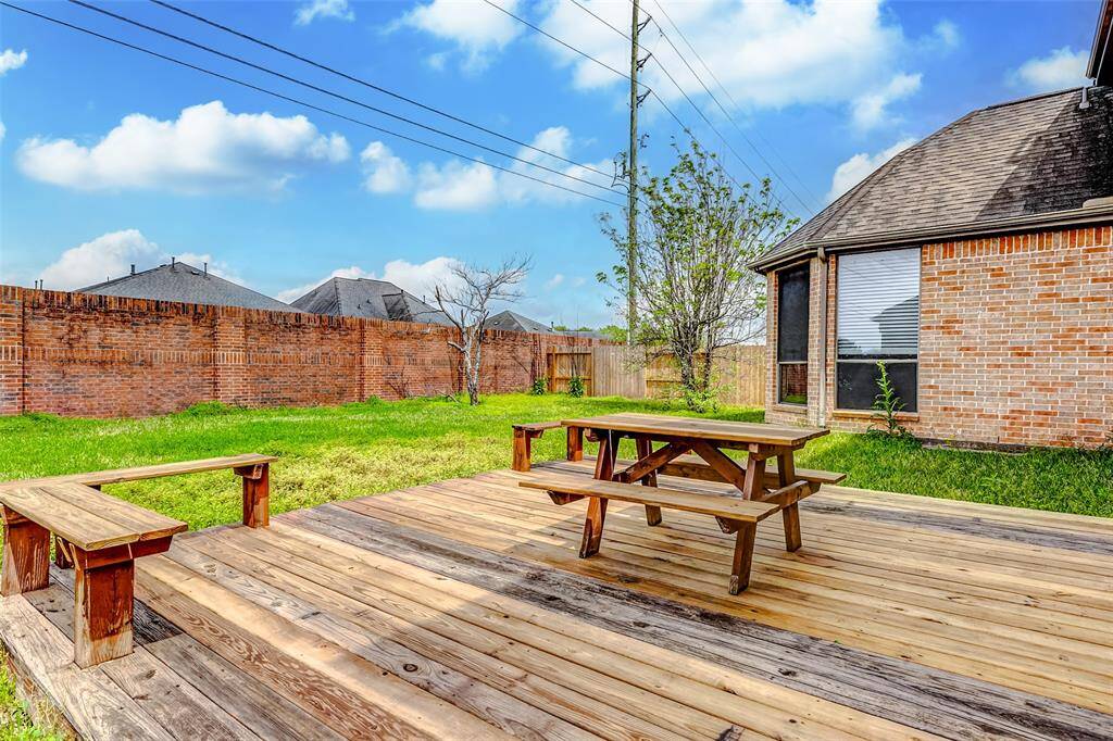 Spacious backyard with a wooden deck, built-in benches, and a picnic table
