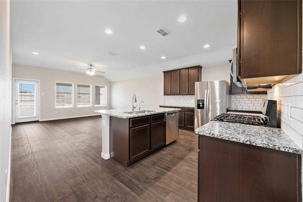 Incredibly trendy kitchen area features subway tile backsplash, granite countertops, bar area, all stainless steel appliances, and opens up to the living room! This stunning new laminate runs through the entire main area of the home, including this formal dining with quick access to the kitchen.