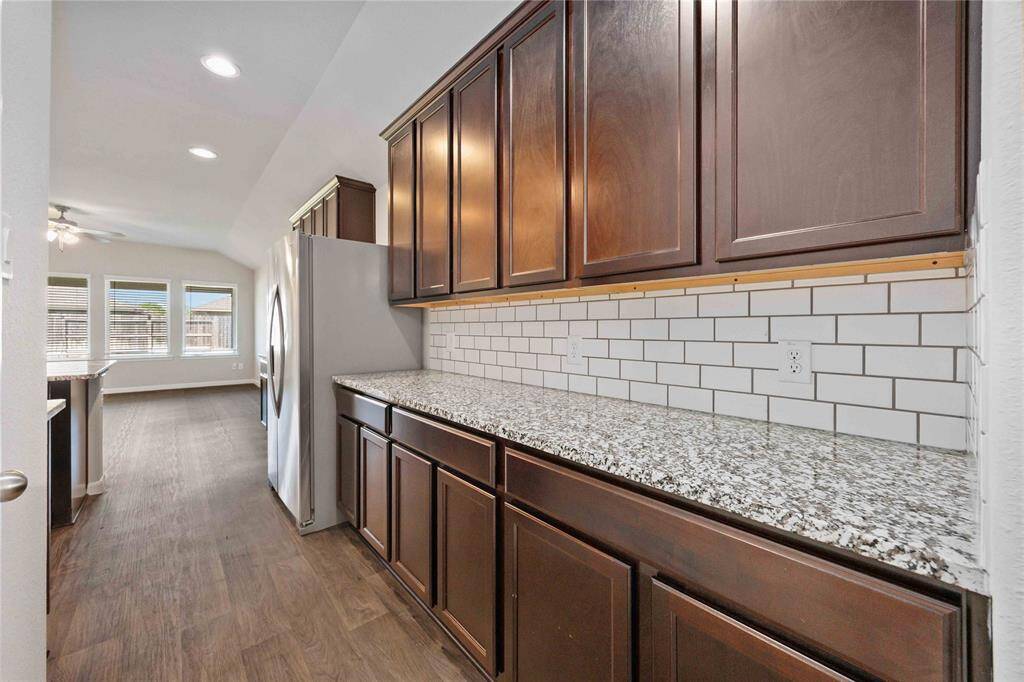 Modern farmhouse charm. Dark cabinets, a speckled granite countertop, and subway tile create a timeless aesthetic. A space for both everyday meals and special occasions.