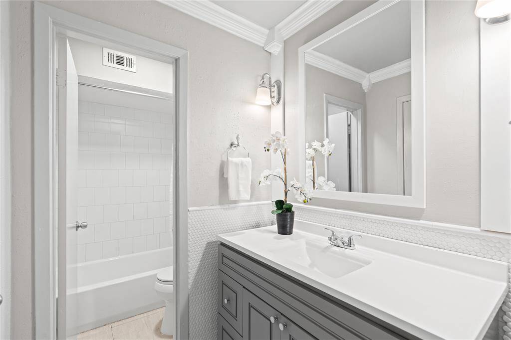 The primary bath was recently renovated and includes a lovely vanity, framed mirror, and artistic lighting.