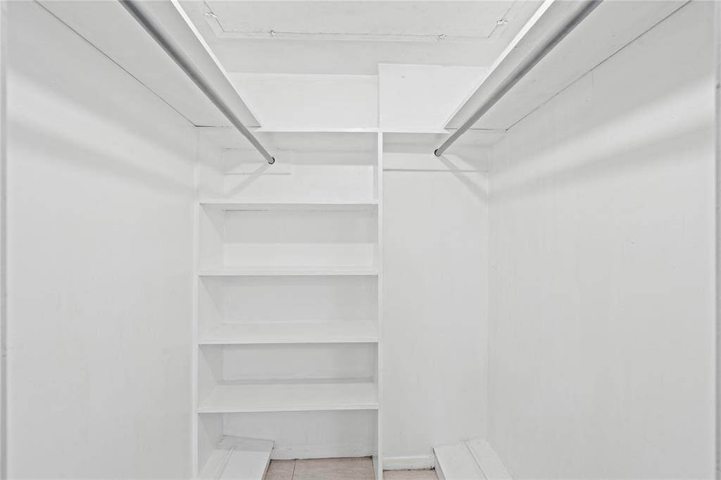 The walk-in closet features built-in shelving including shoe ledges.