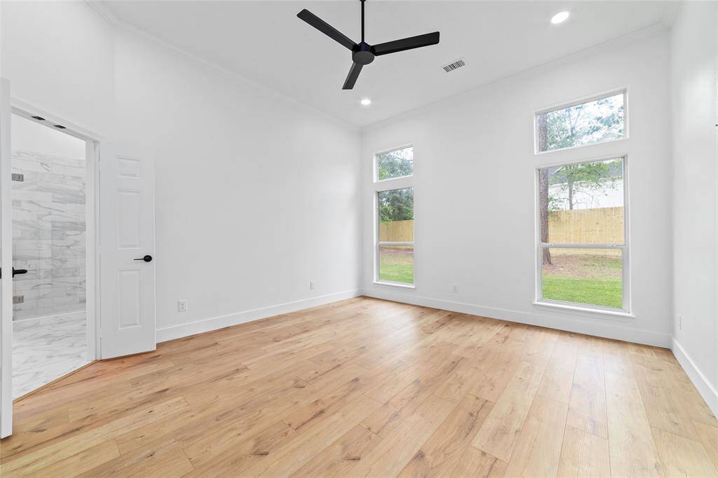 Elegant first-floor primary bedroom with wood floors and a ceiling fan.