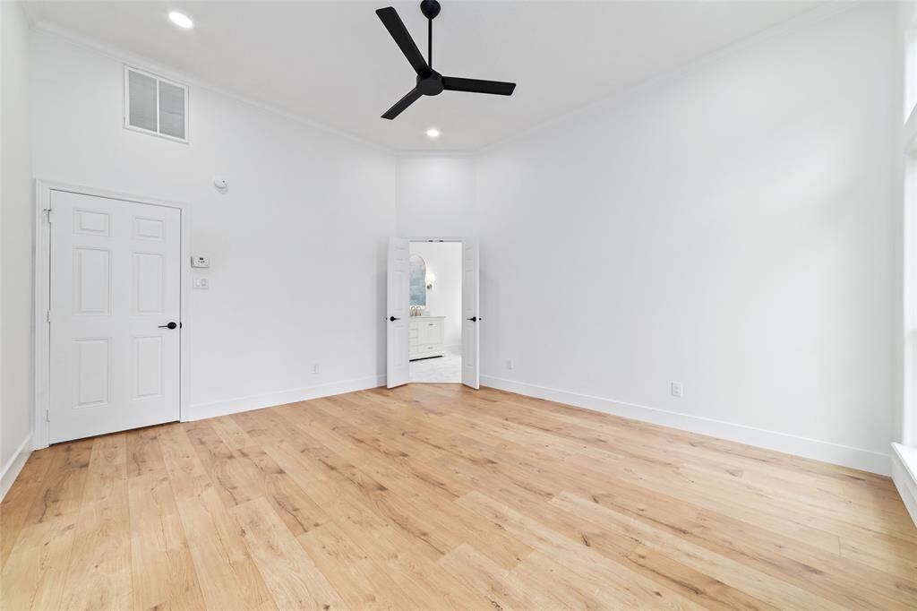 Spacious primary bedroom with elegant wood flooring and abundant natural light.