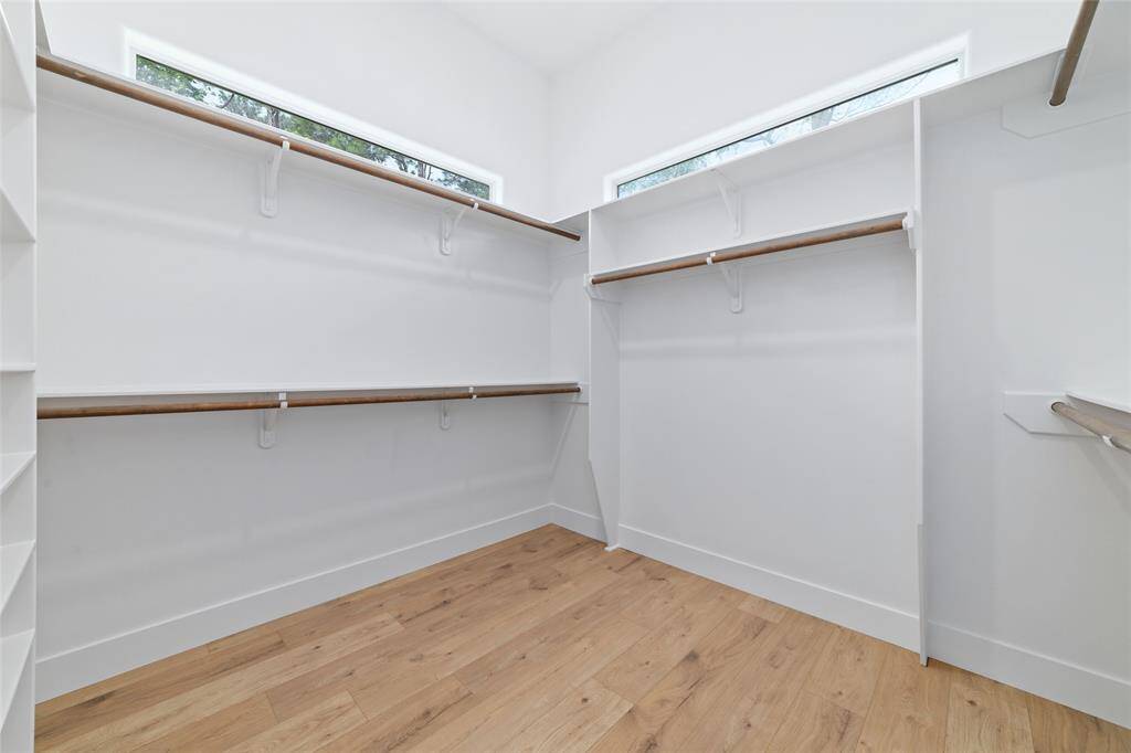 Spacious primary closet featuring elegant wood shelving and abundant natural light.