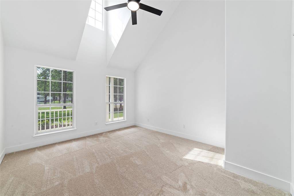 Downstairs bedroom featuring plush carpeting, soaring cathedral ceilings, and a modern ceiling fan.