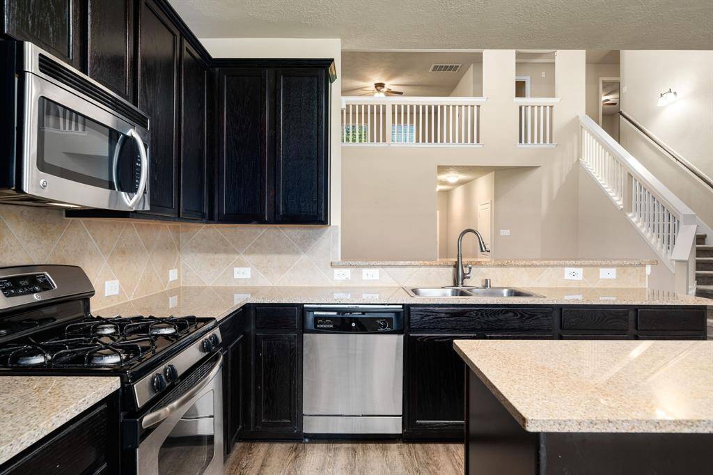 Sleek black cabinetry, stainless appliances, and a convenient pass-through design create a stylish, functional hub at the heart of the home.