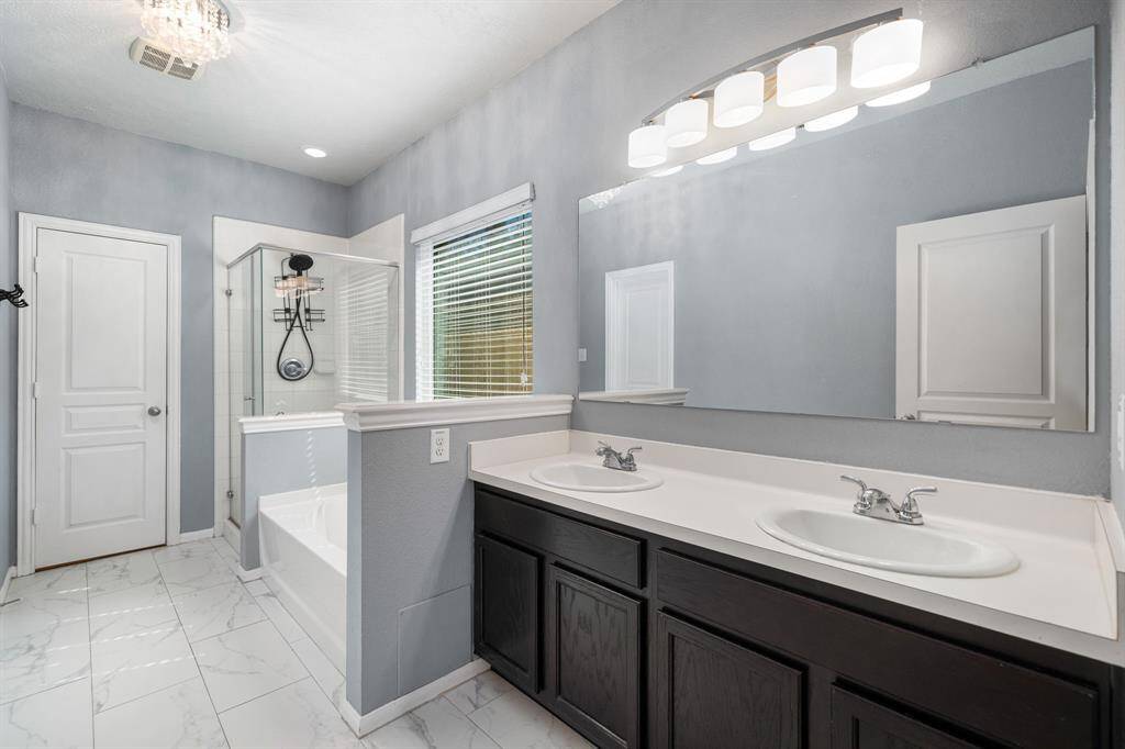 This primary bathroom is definitely move-in ready! Featuring a dark framed walk-in shower with tile surround, separate garden tub for soaking after a long day with custom tile detailing, dark stained cabinets with light countertops, spacious walk-in closet with shelving, high ceilings, custom paint, sleek and dark modern finishes.