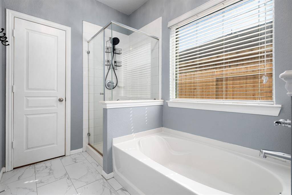 This additional view of the primary bath showcases a walk-in shower with tile surround and a separate garden tub perfect for soaking after a long day.